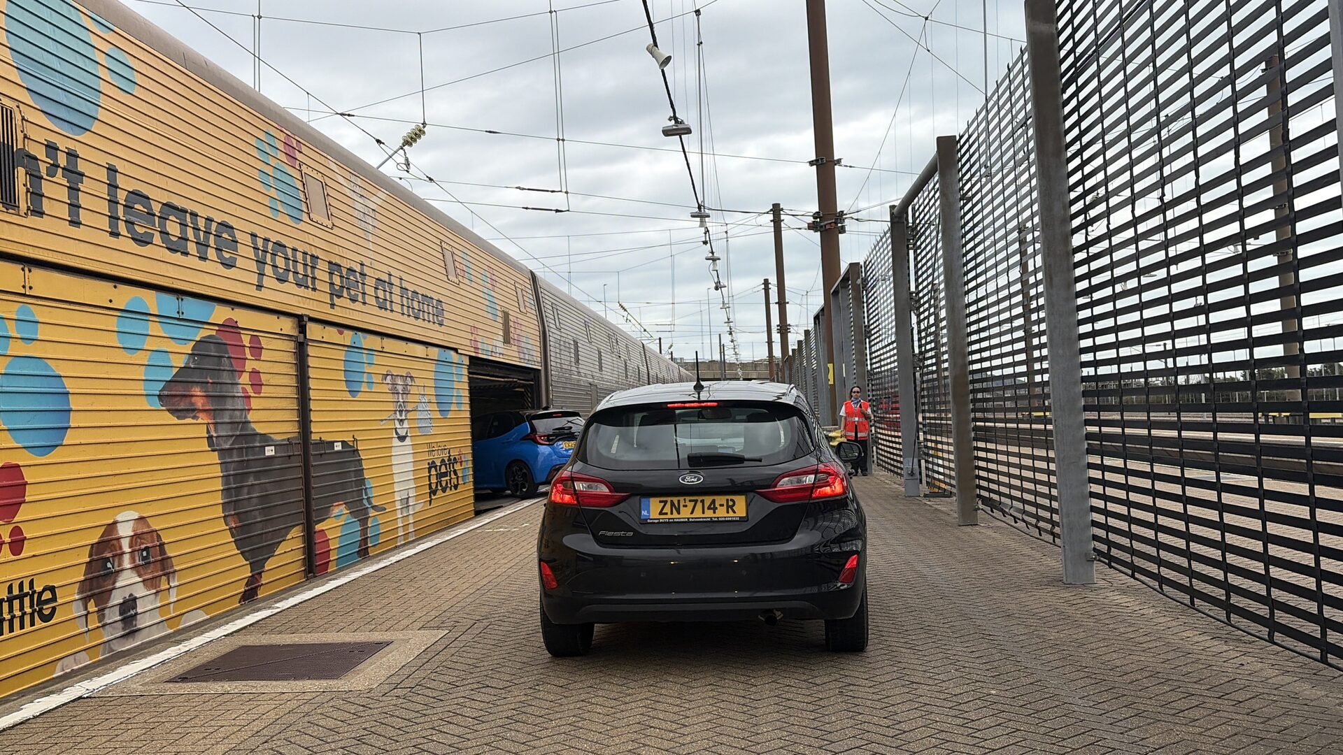 Car driving into a LeShuttle carriage at Folkestone guided by a member of staff